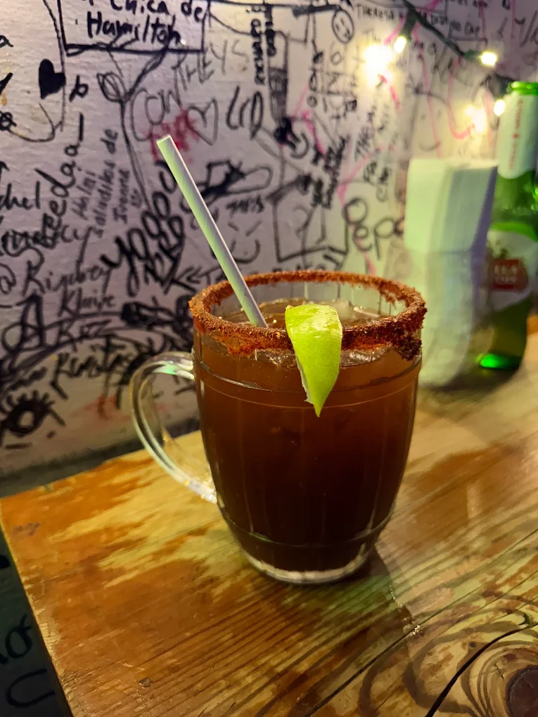 A lime-topped michelada against Piñata Tacos’ handwritten wall