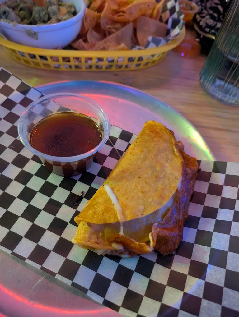Golden quesabirria with melted cheese and a side of birria consommé