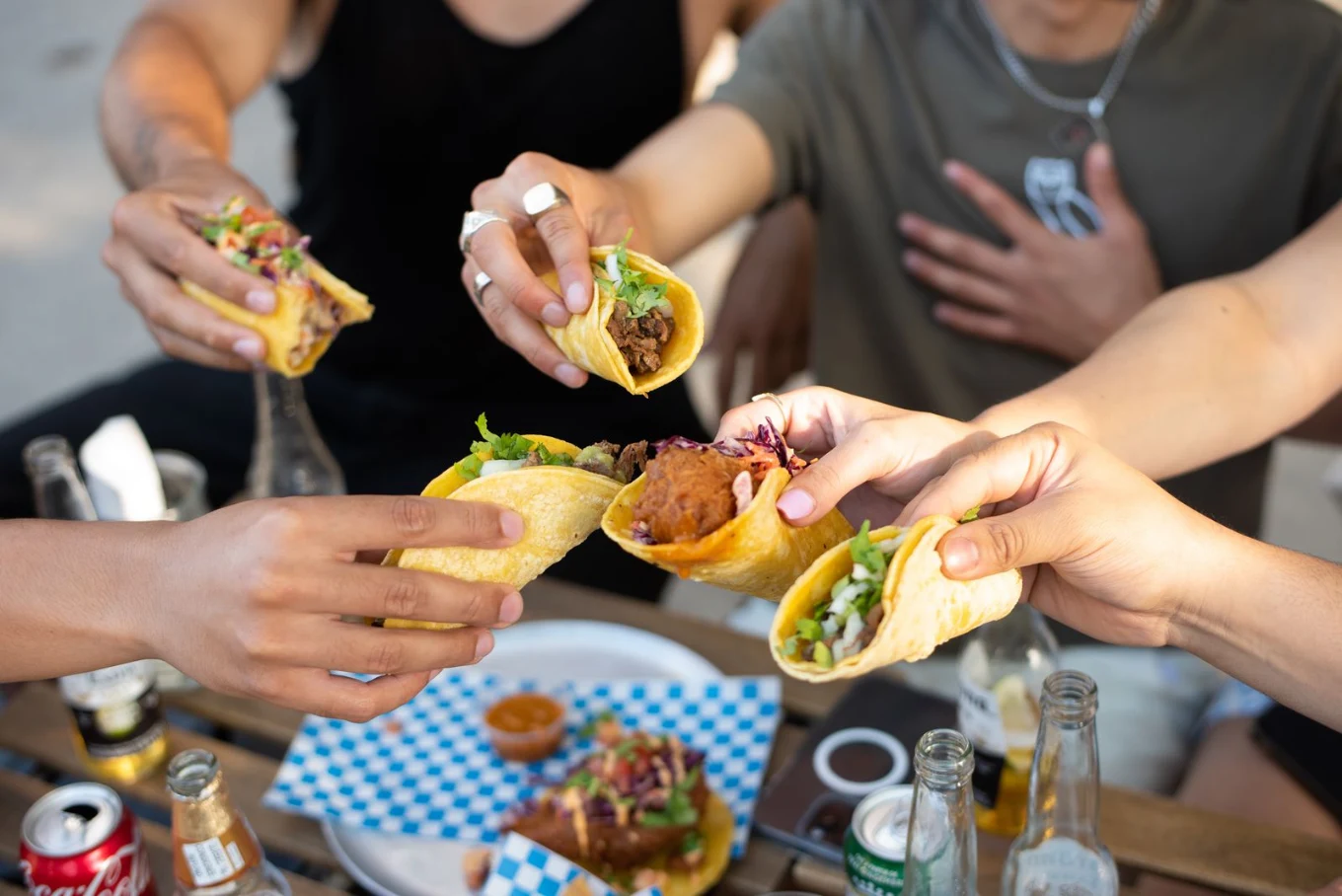 Friends bringing their tacos together around a table at Piñata Tacos